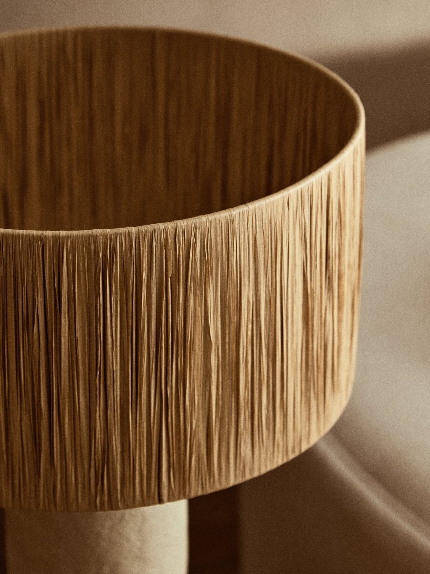 Natural table lamp with tall base and soft pleated shade, close up shade detail