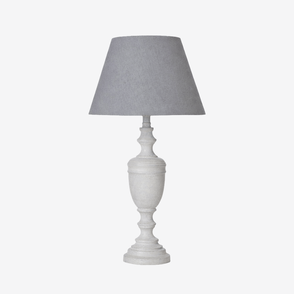 A table lamp with a textured gray fabric drum shade and a distressed white ceramic or stone urn-style base, shown against a plain light gray background.