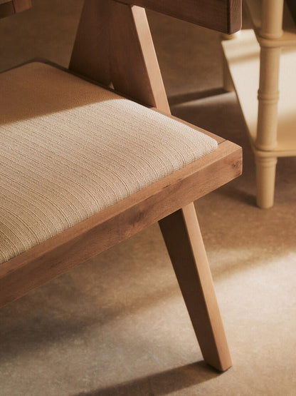 Ivory fabric upholstered armchair with beech wood frame, close up